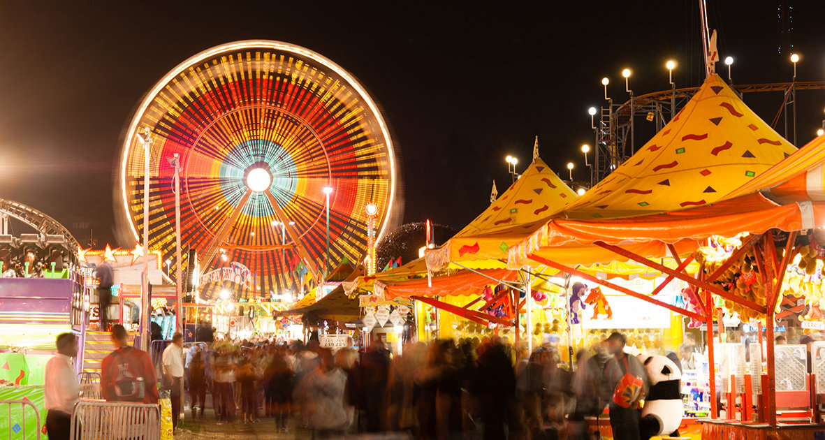 Belebte Kilbi bei Nacht mit Riesenrad und Marktständen